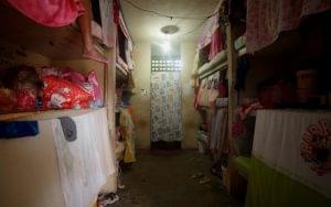 Cela escura em prisão feminina com camas em beliche.